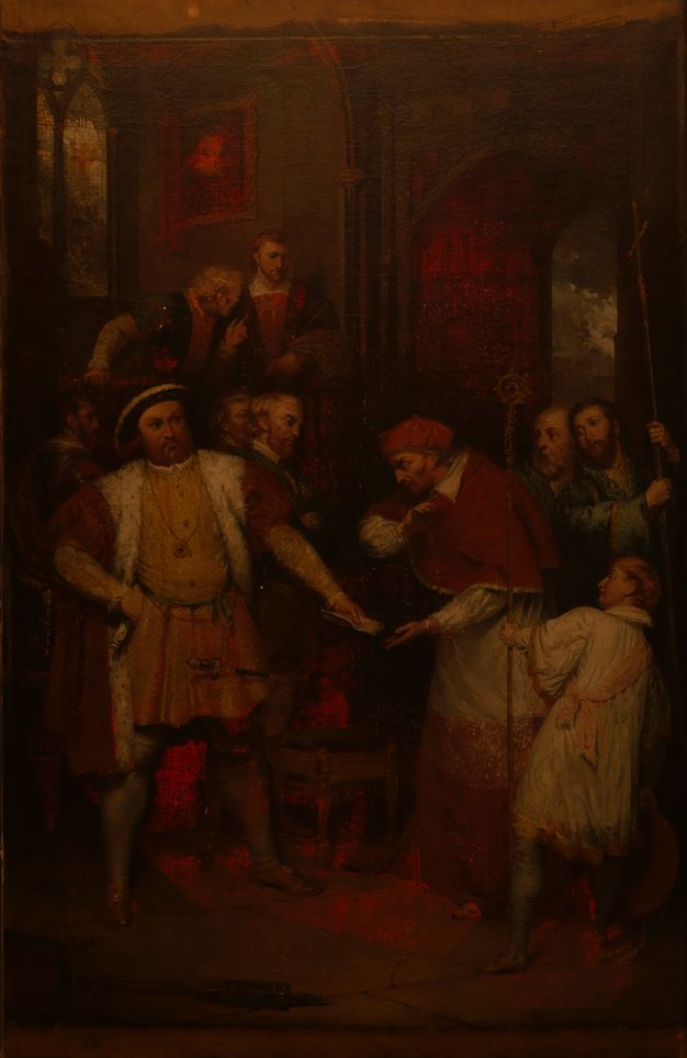 Painting. A man, Henry VIII, stands with feet widely planted, one hand on his hip as he hands a piece of paper to Thomas Wolsey, who wears red cardinal’s robes. The tones are dark and shadowy except where the red glows as the canvas is lit from behind.
