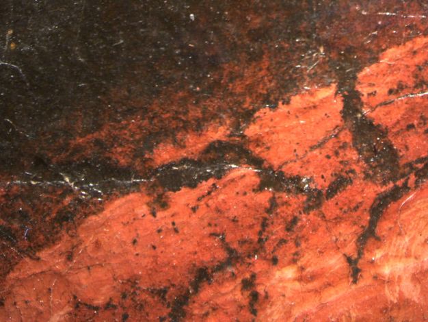 Painting. Detail view of cracks in red paint showing a brown layer beneath.